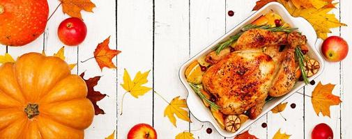 Roasted turkey garnished with cranberries on a rustic style table decorated with pumpkins, orange, apples and autumn leaf. Thanksgiving Day. Flat lay. Top view. Banner photo