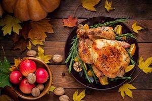 Roasted turkey garnished with cranberries on a rustic style table decorated with pumpkins, orange, apples and autumn leaf. Thanksgiving Day. Flat lay. Top view photo