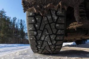 La banda de rodadura de los neumáticos con clavos de invierno se encuentra en el ventisquero cerca después de una fuerte tormenta de nieve en invierno foto
