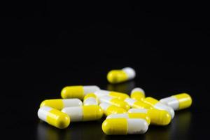 White tablet with two pills in background. Black background with reflection. photo