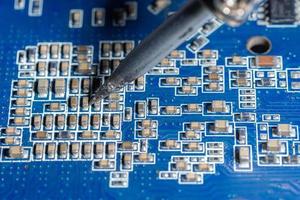 Repairman is soldering the motherboard of electronic device. photo