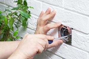 Electrician disassembling wall socket in new building, closeup photo