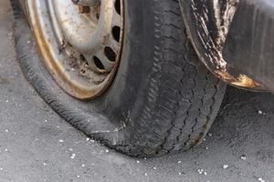 Neumático pinchado de coche de primer plano en la carretera. foto