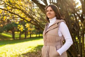 portrait of a strong young brown-haired woman walking in the autumn park photo