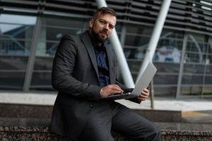 businessman in a suit with a laptop on the background of a business center photo