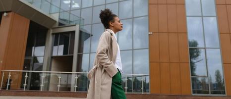 joven afroamericana caminando frente al edificio administrativo