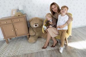 happy mom with two male children in the children's room having fun photo