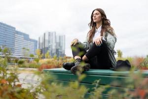 Meditation of an office employee on a park bench in a yoga position against the backdrop of office buildings photo