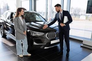 a representative of a car dealership demonstrates a car to a buyer photo