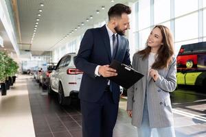 an employee of a car dealership helps to sort out a car insurance buyer woman photo