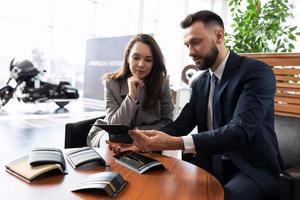 car dealership manager helping young woman choose car trim when buying it at car dealership, car rental concept photo