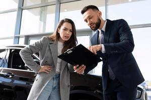 young woman buyer in a car dealership understands the nuances of the contract when buying a new car photo