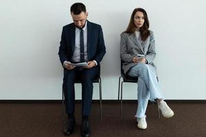 dos jóvenes profesionales en trajes de negocios esperando en línea para una entrevista foto