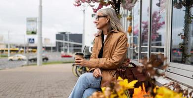 fifty year old strong woman drinking coffee while sitting in the city photo