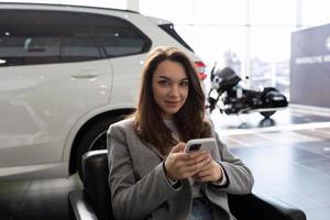 mujer joven en un concesionario de automóviles esperando a un gerente de ventas de automóviles nuevos foto