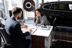 a young girl buys a car in a car dealership on credit and arranges it with a manager photo