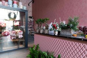 stand with natural flowers and fir-tree composition in the foreground in the interior of a stylish shop selling flowers and bouquets photo