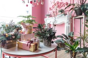 Christmas compositions from natural fir and gift boxes and with Christmas gifts in a stylish pink interior photo