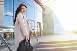 successful business woman enters the business center with a briefcase in her hands, strong and independent woman concept photo