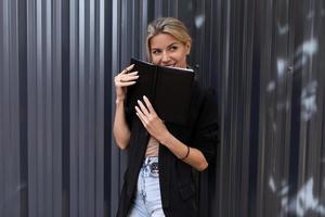 office worker middle-aged woman with a smile holding a notebook in her hands looking at the camera photo