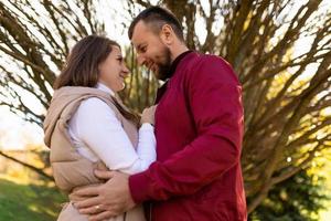 una pareja casada adulta se pone de pie entre sí contra el fondo de un árbol de otoño ramificado foto