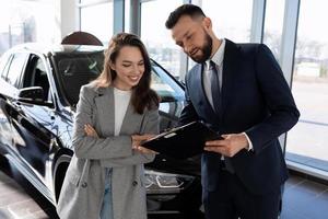 car dealership consultant talks about the loan program to the buyer of a new car, car insurance concept photo