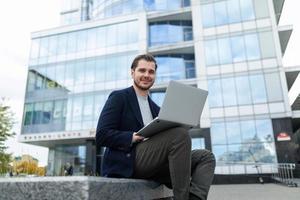 successful businessman works remotely online outdoors outdoors against the backdrop of a city building photo