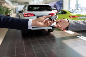 car dealership consultant handing over the keys to the buyer close-up on the background of new cars photo