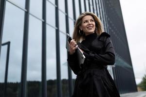 portrait of a successful business woman with a laptop in her hands against the backdrop of an office skyscraper photo