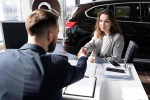 completion of a deal in a car dealership for the sale of a new car of a young girl, car rental concept photo