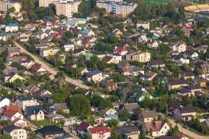aerial panoramic view of green village with homestads, houses, barns and gravel road in forest photo