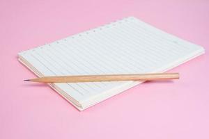 Top view image of notebook with pencils on pink background photo