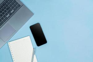 Top view of Office Table top with laptop computer, pen, balck smart phone and notebook with space photo