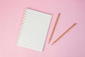 Top view image of notebook with pencils on pink background photo