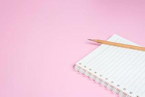 Top view image of notebook with pencils on pink background photo