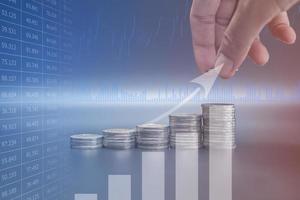 Double exposure hand stacking Thailand coins on black background with profit graph photo