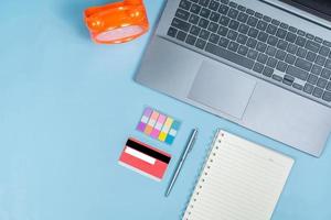 Top view of Office Table top with laptop computer, orange clock, notebook, credit card, pen with space photo