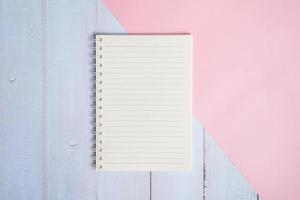 Top view image of notebook on wooden table with pink background photo