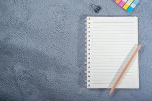 Top view image of notebook with pencil, colorful mini paper note and paper clip on gray carpet photo