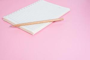 Top view image of notebook with pencils on pink background photo