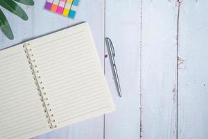 Top view image of notebook with pen and xanadu leaf on wooden table photo