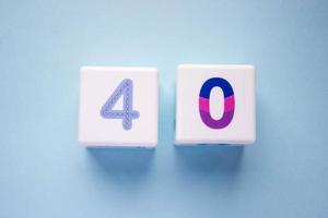 Close-up photo of a white plastic cubes with a colorful number 40 on a blue background. Object in the center of the photo