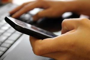 The girl sits at a laptop and holds a smartphone in her hands. Business concept. Online Shopping. Blurred background. photo