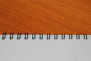 Notepad on a wooden table with copy space. View from above. Design blank. photo