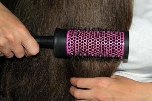 A girl with dark long hair combs her hair. Hair care. Hair loss problem. photo