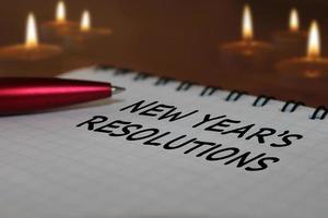 cuaderno con un bolígrafo sobre una mesa de madera con el telón de fondo de velas encendidas. el concepto de resoluciones para el nuevo año. foto