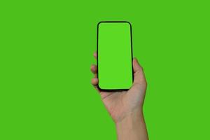 A woman's hand holds a smartphone with a green screen. Isolated object on a green background. Template for design. Mocap. photo