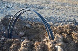 a large metal arc protrudes from the brown sand in the center of the city. construction of a new residential complex. dangerous areas, obstacles from people. life threatening photo