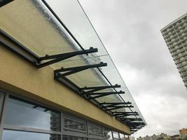 marquesina de cristal para recoger las gotas de lluvia. el techo del centro comercial sobre fortificaciones negras para proteger el edificio de las precipitaciones húmedas. fortificación de vidrio contra un cielo nublado foto