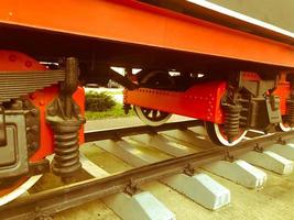 Large iron wheels of a red and black train standing on rails and suspension elements with springs of an old industrial steam locomotive photo